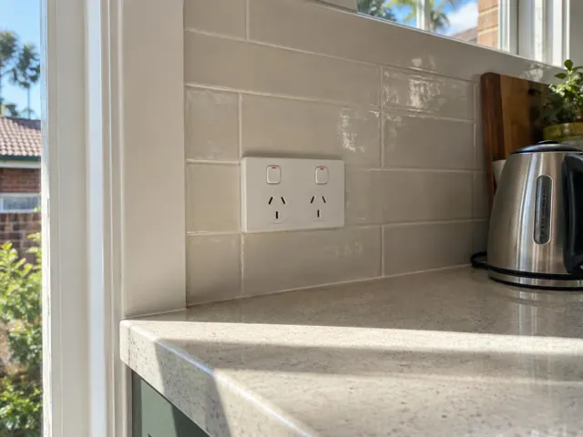 Double power point on glossy tiled kitchen splashback above a benchtop in Fairlight